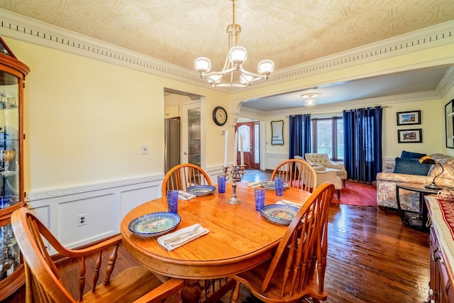 dining area featuring dark hardwood / wood-style floors, an inviting chandelier, and crown molding