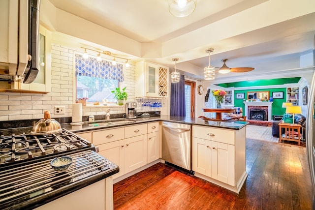 kitchen featuring dishwasher, sink, hanging light fixtures, dark wood-type flooring, and kitchen peninsula