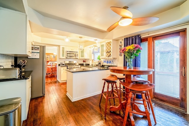 kitchen with white cabinets, appliances with stainless steel finishes, tasteful backsplash, and dark wood-type flooring