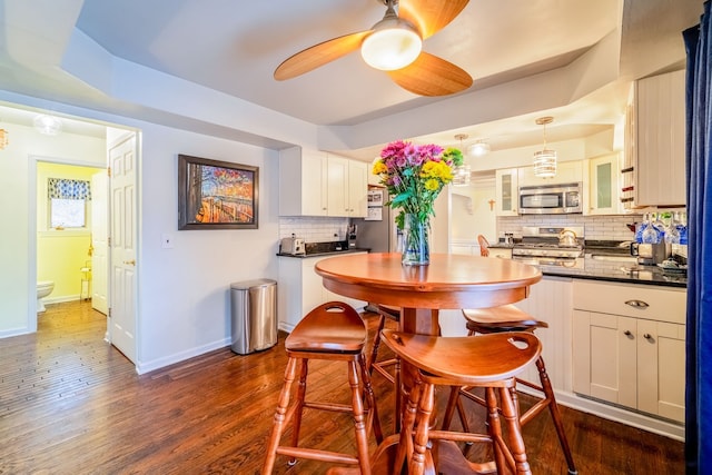 kitchen with stainless steel appliances, dark hardwood / wood-style floors, decorative light fixtures, decorative backsplash, and white cabinets