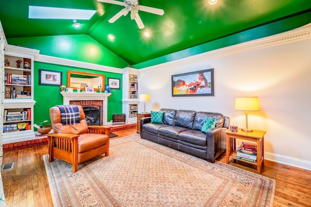 living room with a brick fireplace, lofted ceiling with skylight, ceiling fan, and hardwood / wood-style flooring