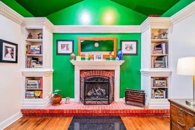 living area with hardwood / wood-style floors, built in features, lofted ceiling, and a fireplace