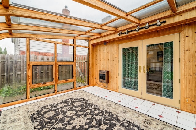 unfurnished sunroom with beam ceiling, heating unit, and french doors