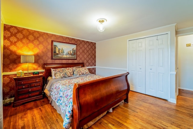 bedroom with hardwood / wood-style flooring, crown molding, and a closet