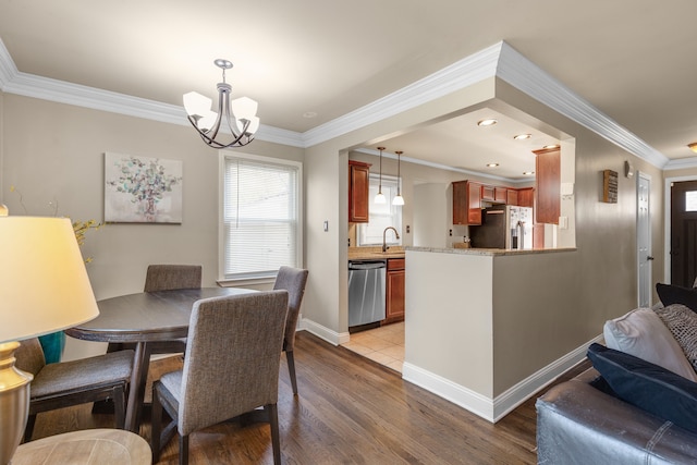 dining room with ornamental molding, a chandelier, sink, and light wood-type flooring