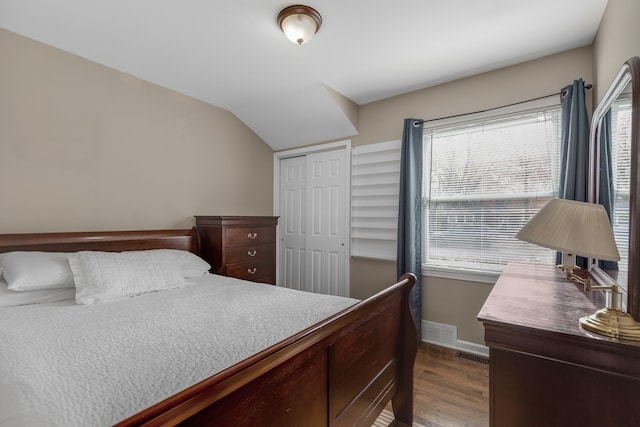 bedroom featuring dark hardwood / wood-style flooring, vaulted ceiling, and a closet