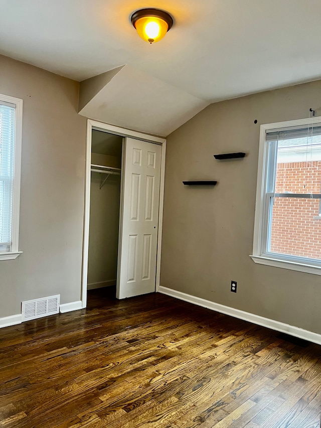 unfurnished bedroom with dark wood-type flooring, a closet, and vaulted ceiling