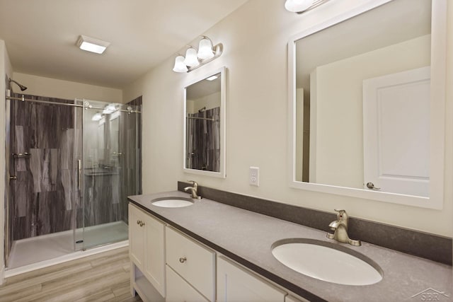 bathroom with hardwood / wood-style floors, vanity, and a shower with shower door