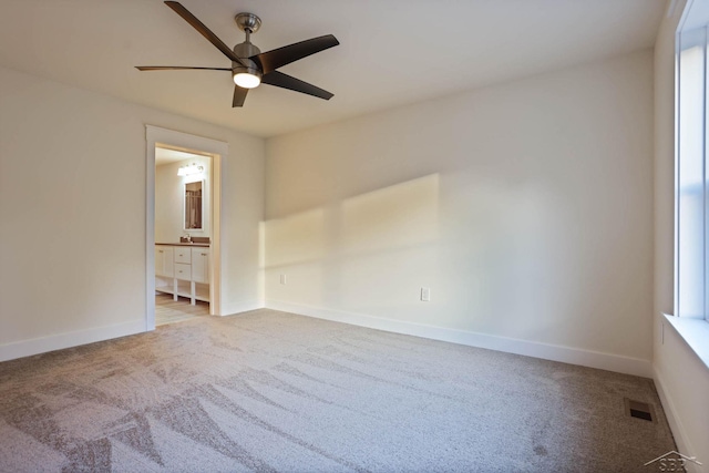 carpeted spare room with ceiling fan and plenty of natural light