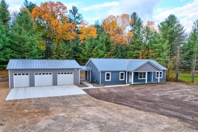 2210 Fox Run Rd, West Branch, MI 48661 - single story home featuring dirt driveway, an outbuilding, metal roof, a porch, and a detached garage