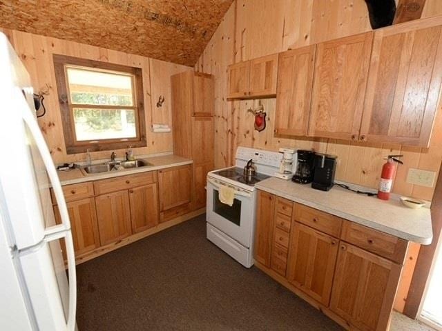 kitchen with wooden walls, sink, and white appliances