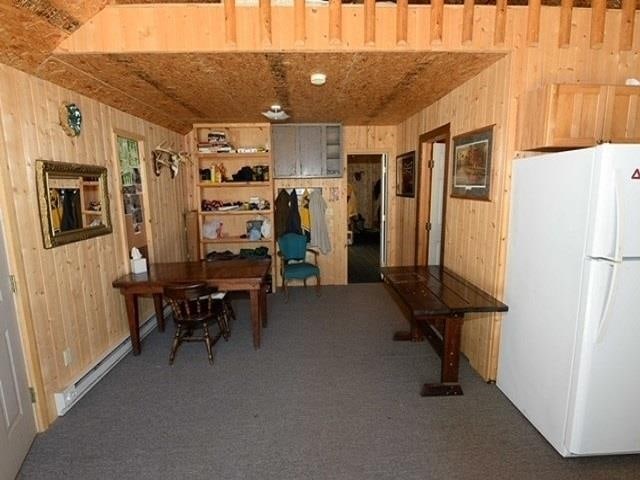 interior space featuring wooden walls and a baseboard heating unit