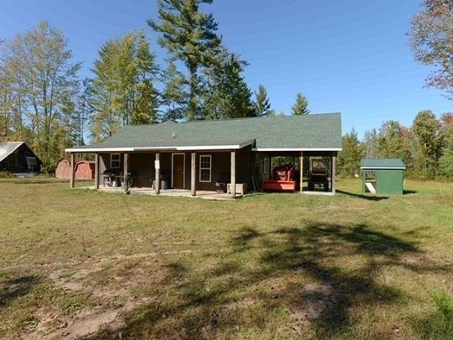 back of house with a storage shed and a lawn