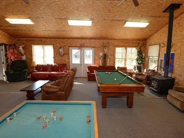 recreation room with carpet floors, a wood stove, lofted ceiling, and pool table