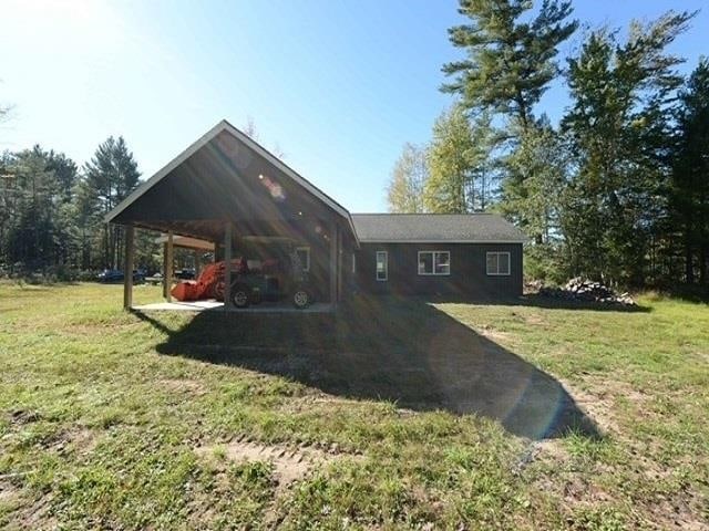 back of property featuring a lawn and a carport