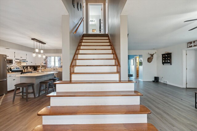 staircase with hardwood / wood-style flooring and sink