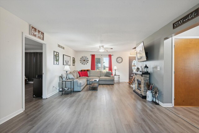 16248 Wabash Rd, Waldron, MI 49288 - living room featuring wood finished floors, ceiling fan, baseboards, and a stone fireplace