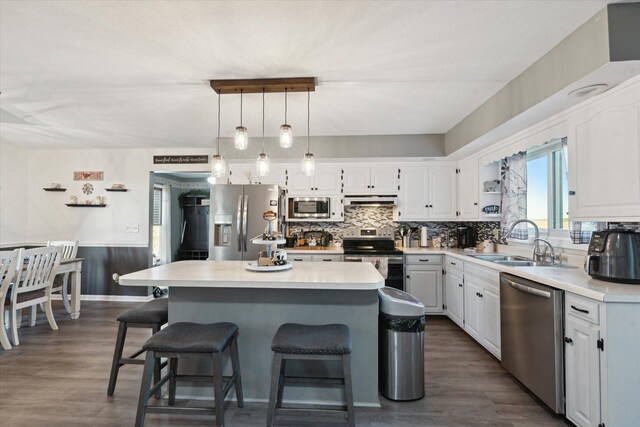 kitchen with dark wood-type flooring, sink, appliances with stainless steel finishes, a kitchen island, and white cabinetry