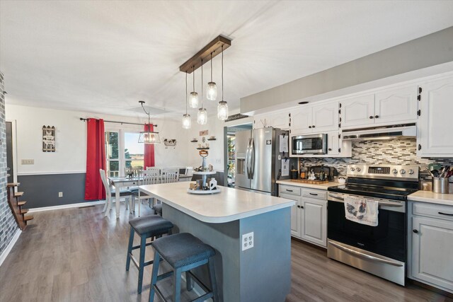 kitchen featuring white cabinets, appliances with stainless steel finishes, a kitchen island, and dark wood-type flooring