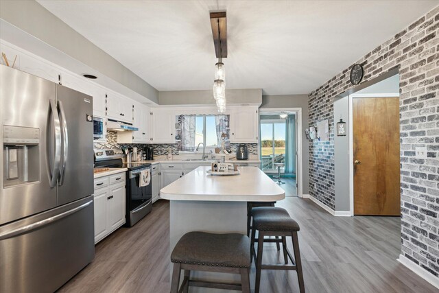 16248 Wabash Rd, Waldron, MI 49288 - kitchen with appliances with stainless steel finishes, a sink, light countertops, wood finished floors, and brick wall