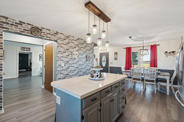 16248 Wabash Rd, Waldron, MI 49288 - kitchen with gray cabinetry, wood finished floors, light countertops, a kitchen island, and brick wall