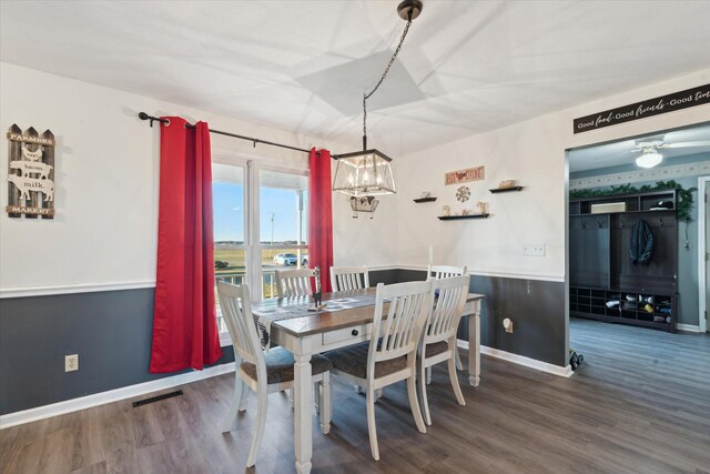 dining area featuring ceiling fan with notable chandelier and dark wood-type flooring