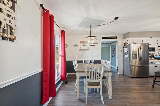 dining area with dark hardwood / wood-style flooring and a notable chandelier