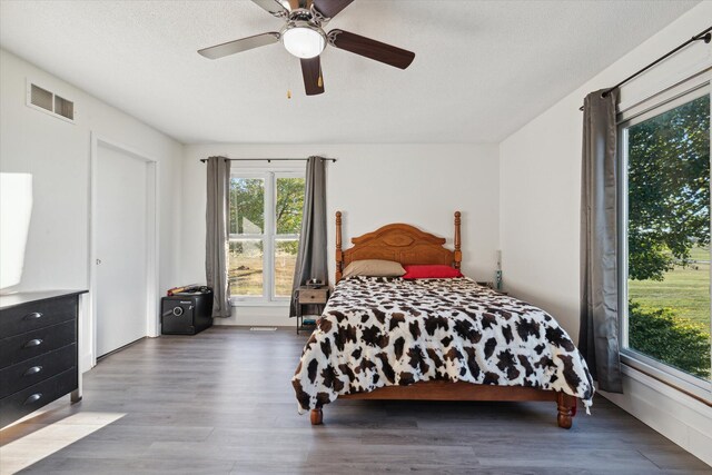 bedroom with ceiling fan, wood-type flooring, and a textured ceiling