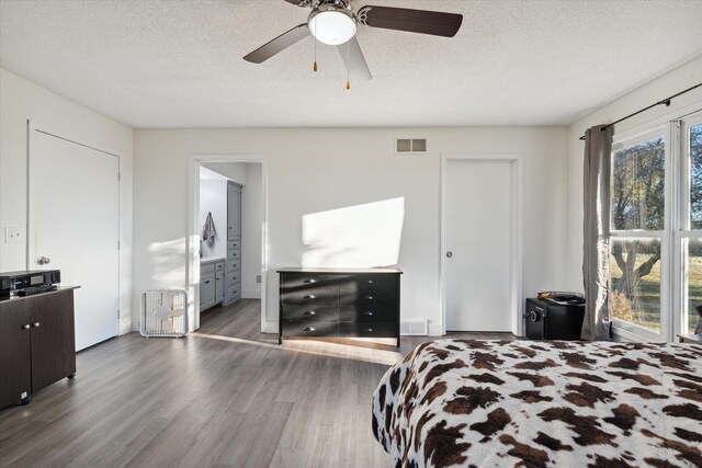 bedroom featuring a textured ceiling, ensuite bathroom, ceiling fan, and dark hardwood / wood-style floors