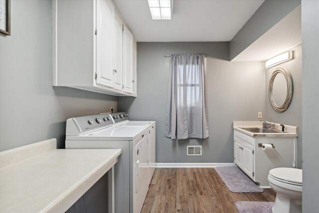 clothes washing area featuring washing machine and dryer, light hardwood / wood-style floors, and sink