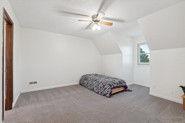 bedroom featuring carpet, ceiling fan, lofted ceiling, and a textured ceiling