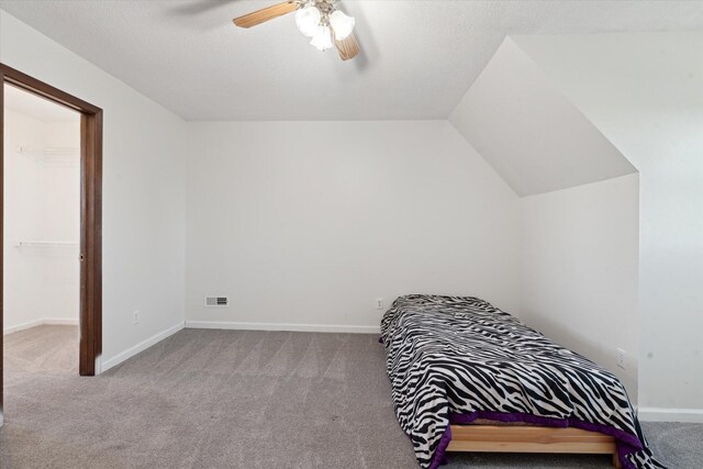 carpeted bedroom featuring ceiling fan, a closet, a spacious closet, and vaulted ceiling