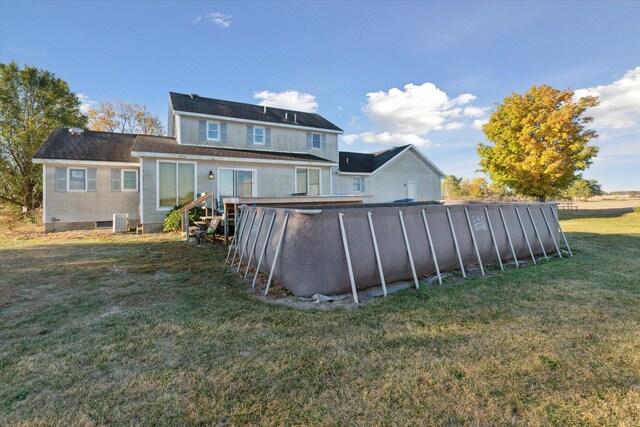 back of property featuring a lawn, central AC, and a swimming pool