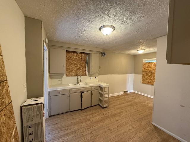 kitchen with light hardwood / wood-style flooring, a textured ceiling, and sink