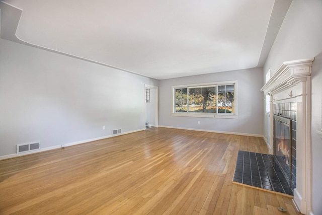 unfurnished living room featuring a tile fireplace and light wood-type flooring