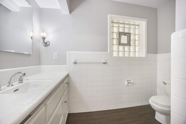 bathroom with hardwood / wood-style flooring, vanity, toilet, and tile walls