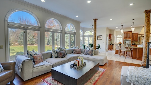 living room with plenty of natural light, light wood-type flooring, and ornamental molding