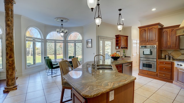 kitchen with a center island with sink, decorative light fixtures, sink, and appliances with stainless steel finishes