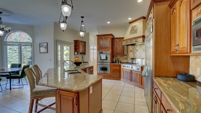 kitchen with appliances with stainless steel finishes, a kitchen island with sink, a healthy amount of sunlight, sink, and pendant lighting