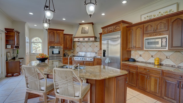 kitchen featuring a kitchen island with sink, sink, built in appliances, decorative light fixtures, and custom range hood