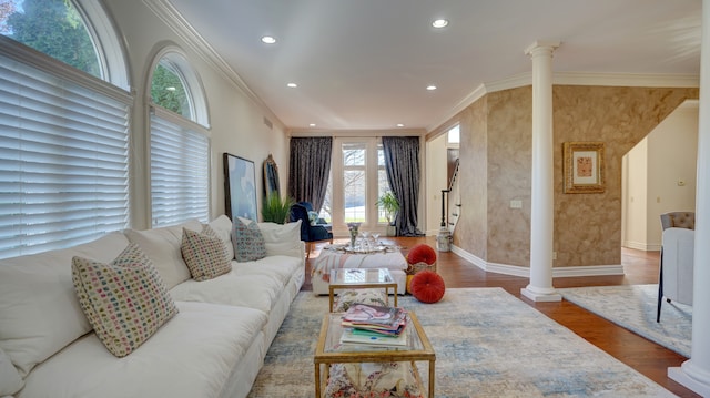 living room with a healthy amount of sunlight, ornate columns, dark wood-type flooring, and crown molding