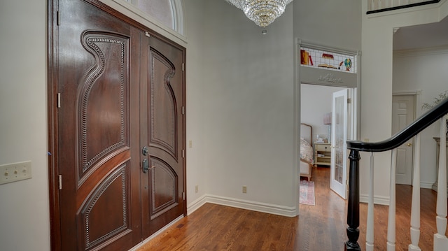 foyer entrance featuring crown molding, hardwood / wood-style floors, and a chandelier