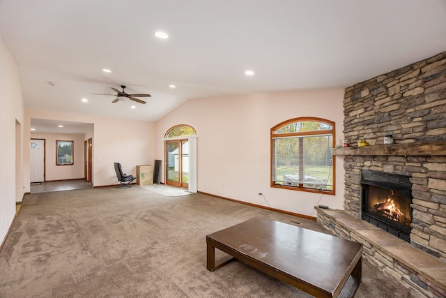 unfurnished living room with carpet flooring, a stone fireplace, ceiling fan, and vaulted ceiling