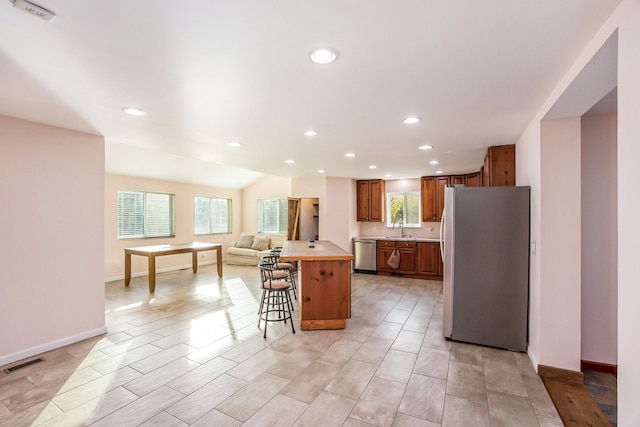 kitchen with a kitchen bar, sink, a kitchen island, and appliances with stainless steel finishes