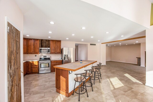 6700 Bethuy Rd, Ira, MI 48023 - kitchen with stainless steel appliances, a breakfast bar area, recessed lighting, brown cabinetry, and a center island