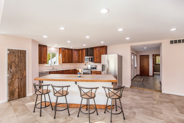 kitchen featuring a kitchen breakfast bar, a center island, sink, and appliances with stainless steel finishes