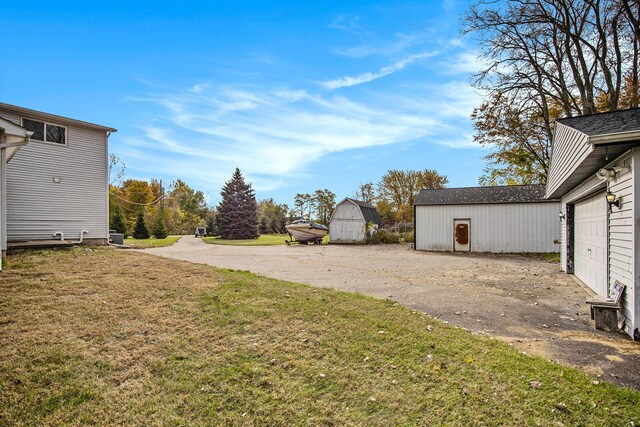 6700 Bethuy Rd, Ira, MI 48023 - view of grassy yard featuring an outbuilding, a garage, and driveway