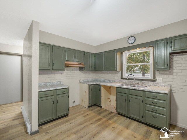 6405 Stillwater Ct, Erie, MI 48133 - kitchen with green cabinetry, under cabinet range hood, a sink, backsplash, and light wood-type flooring