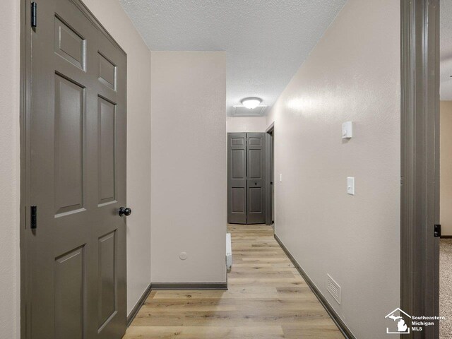 6405 Stillwater Ct, Erie, MI 48133 - hallway featuring light wood finished floors, a textured ceiling, and baseboards