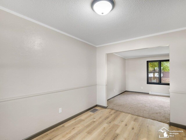 6405 Stillwater Ct, Erie, MI 48133 - empty room with a baseboard radiator, baseboards, wood finished floors, ornamental molding, and a textured ceiling